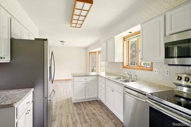321 Myers Rd, Lapeer, MI 48446 - kitchen with appliances with stainless steel finishes, a sink, light wood-style floors, a peninsula, and decorative backsplash