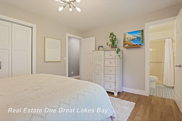 4936 Frontier Ln, Saginaw, MI 48603 - bedroom featuring a chandelier, baseboards, wood finished floors, a closet, and ensuite bathroom