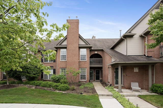 28067 Carlton Way Dr, Novi, MI 48377 - view of front of house featuring roof with shingles, brick siding, a balcony, a front lawn, and a chimney