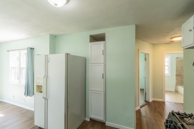 428 Orchard Ave, Muskegon, MI 49442 - kitchen with white refrigerator with ice dispenser, wood finished floors, baseboards, white cabinets, and black range with gas stovetop