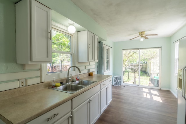 428 Orchard Ave, Muskegon, MI 49442 - kitchen with a sink, ceiling fan, white cabinetry, dark wood-type flooring, and light countertops