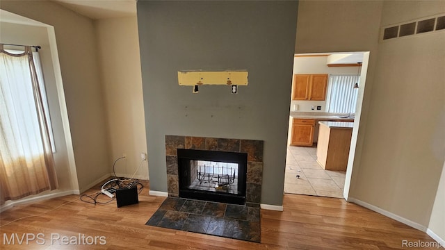 540 Clairpointe Woods Dr, Detroit, MI 48215 - unfurnished living room with light wood-type flooring, a tiled fireplace, and baseboards