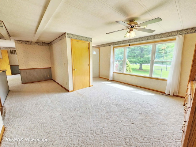 10424 S Graham Rd, Saint Charles, MI 48655 - carpeted spare room with wallpapered walls, a wainscoted wall, a ceiling fan, a textured ceiling, and wooden walls