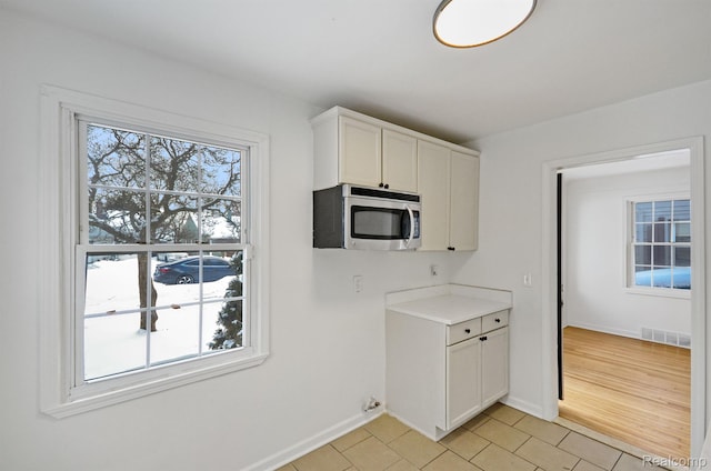 22813 Rosalind Ave, Eastpointe, MI 48021 - kitchen with stainless steel microwave, light tile patterned floors, light countertops, baseboards, and white cabinets
