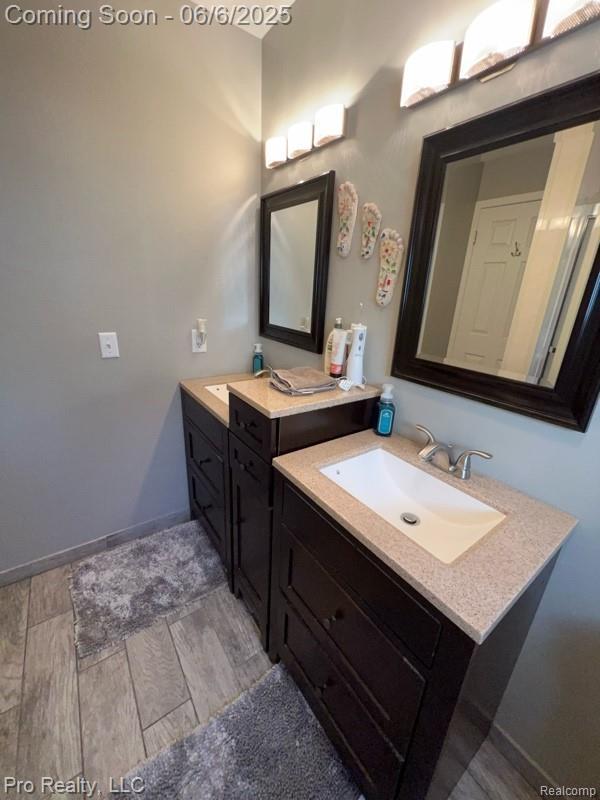 44195 Dartmouth St, Canton, MI 48188 - bathroom featuring two vanities, wood finished floors, and baseboards