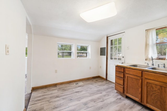 817 Annetta Ave, Jackson, MI 49203 - kitchen with a sink, brown cabinets, electric panel, light wood-type flooring, and vaulted ceiling