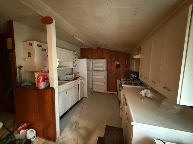 4465 E Old M-63, Luther, MI 49656 - kitchen with lofted ceiling, white cabinetry, wood walls, and under cabinet range hood
