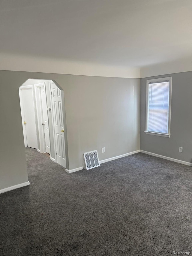 18950 Blackmoor St, Detroit, MI 48234 - empty room with arched walkways, dark colored carpet, and baseboards