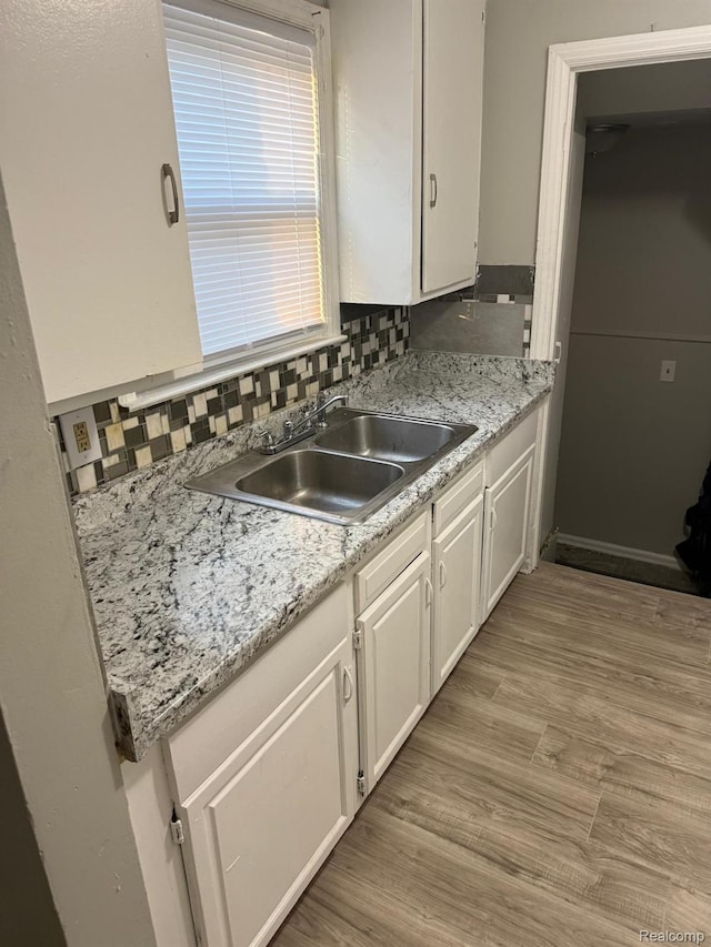 18950 Blackmoor St, Detroit, MI 48234 - kitchen featuring white cabinetry, a sink, light wood finished floors, and backsplash