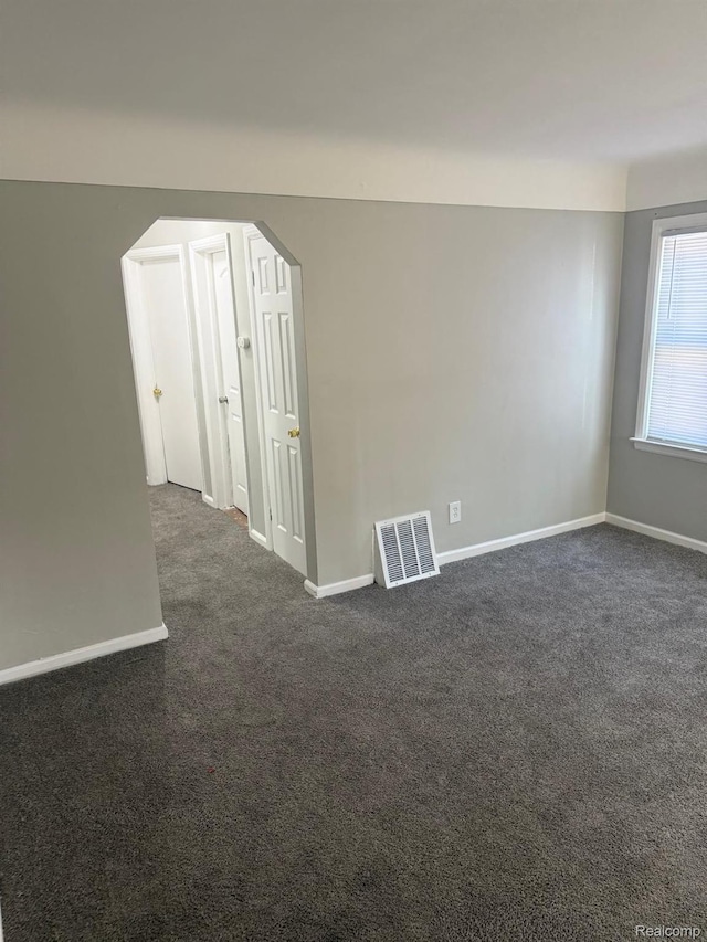 18950 Blackmoor St, Detroit, MI 48234 - empty room with dark carpet, baseboards, and arched walkways