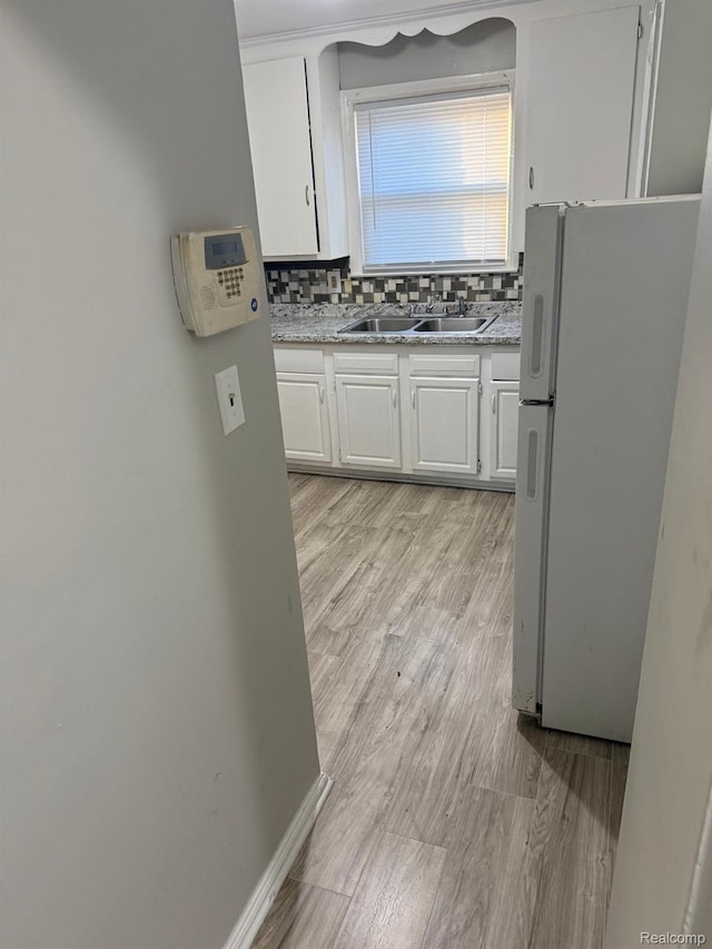 18950 Blackmoor St, Detroit, MI 48234 - kitchen featuring freestanding refrigerator, a sink, white cabinetry, backsplash, and light wood-type flooring
