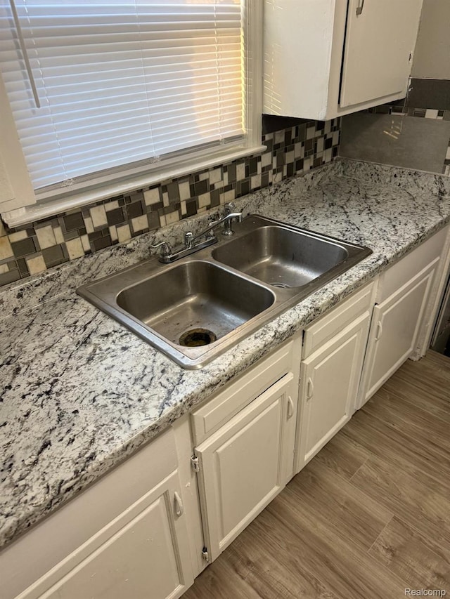 18950 Blackmoor St, Detroit, MI 48234 - kitchen view of a sink, white cabinets, decorative backsplash, and wood finished floors