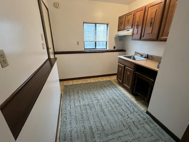 2323 Page Ave, Ann Arbor, MI 48104 - kitchen with a sink, under cabinet range hood, light tile patterned floors, baseboards, and light countertops
