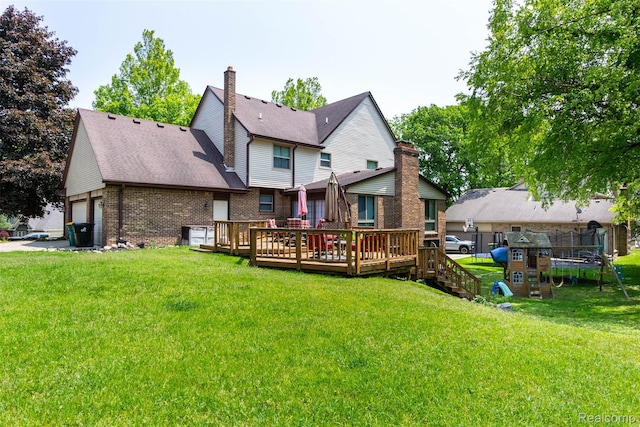 38649 Deerwood Ct, Northville, MI 48167 - back of property with a trampoline, an attached garage, brick siding, a deck, and a lawn