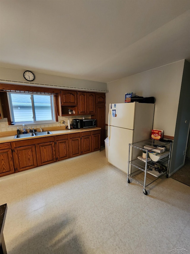 2285 Nebraska Ave, Saginaw, MI 48601 - kitchen featuring stainless steel microwave, a sink, freestanding refrigerator, light floors, and light countertops
