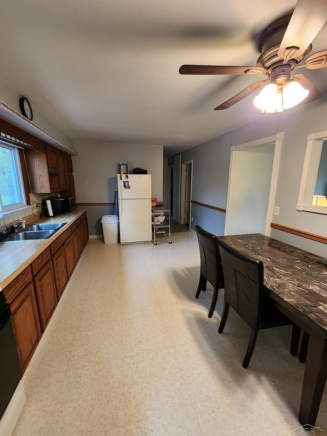 2285 Nebraska Ave, Saginaw, MI 48601 - kitchen with freestanding refrigerator, a sink, a ceiling fan, light flooring, and brown cabinets