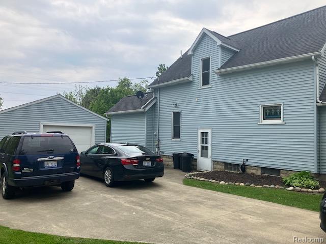 161 Fourth, Harbor Beach, MI 48441 - view of home's exterior with an outbuilding, a detached garage, and roof with shingles