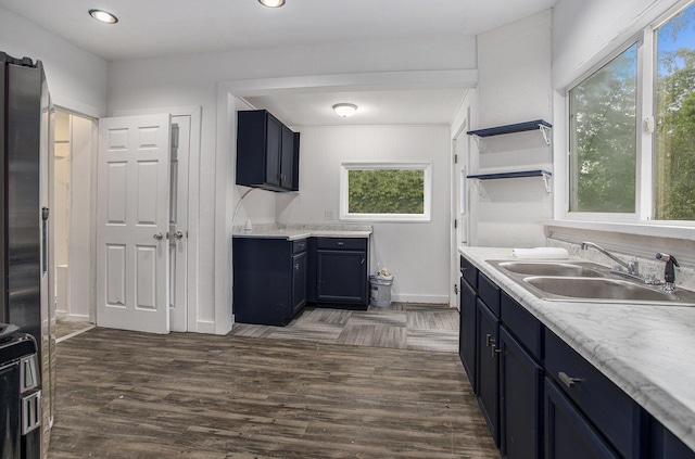 1702 Charles Ave, Kalamazoo, MI 49048 - kitchen featuring a sink, open shelves, light countertops, baseboards, and blue cabinets