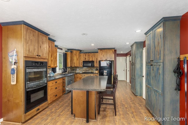 4160 Knapp Valley Dr NE, Grand Rapids, MI 49525 - kitchen with black appliances, dark countertops, a sink, wood finished floors, and a kitchen breakfast bar