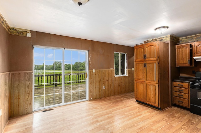 6900 Welch Lake Rd, Grass Lake, MI 49240 - kitchen featuring black range oven, wooden walls, light wood-type flooring, brown cabinetry, and a wainscoted wall