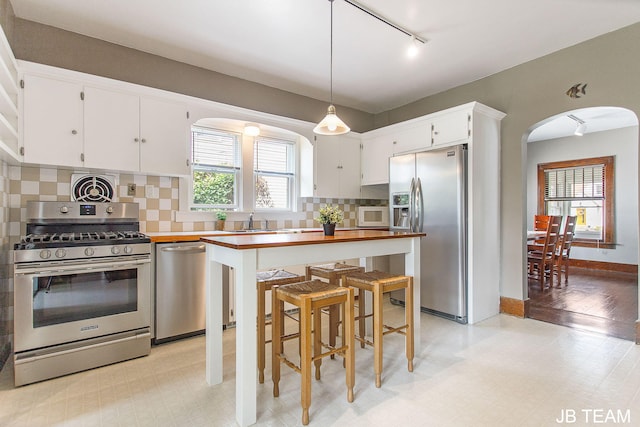 200 W 21st St, Holland, MI 49423 - kitchen featuring stainless steel appliances, arched walkways, rail lighting, tasteful backsplash, and white cabinets