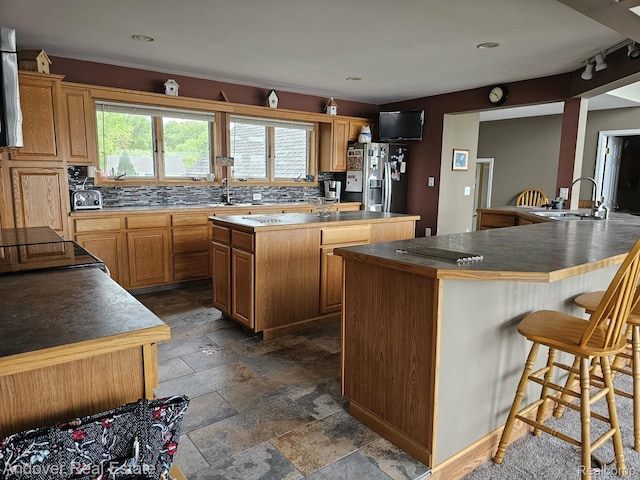 2501 Davista Dr, Highland, MI 48356 - kitchen with a sink, a center island, stainless steel fridge with ice dispenser, stone tile floors, and a breakfast bar area