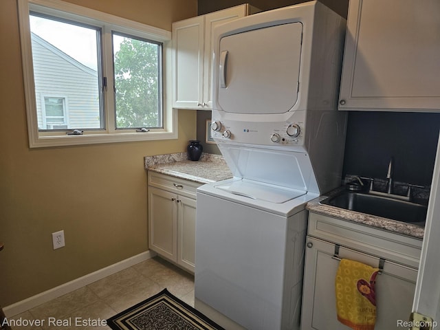 2501 Davista Dr, Highland, MI 48356 - washroom featuring stacked washing machine and dryer, cabinet space, light tile patterned flooring, and baseboards