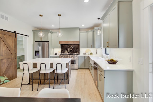 7134 Sugar Maple Dr, Hudsonville, MI 49426 - kitchen with stainless steel appliances, gray cabinetry, a barn door, a kitchen island, and backsplash