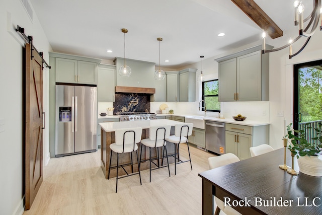 7134 Sugar Maple Dr, Hudsonville, MI 49426 - kitchen featuring appliances with stainless steel finishes, a barn door, light wood-type flooring, a kitchen island, and recessed lighting