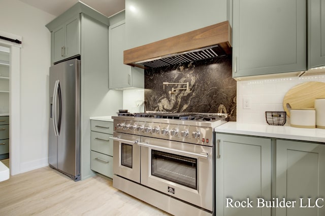 7134 Sugar Maple Dr, Hudsonville, MI 49426 - kitchen featuring appliances with stainless steel finishes, custom exhaust hood, green cabinets, tasteful backsplash, and light wood-type flooring