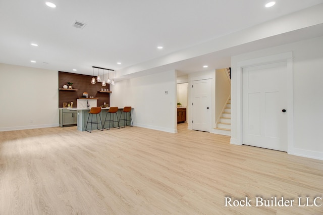 7134 Sugar Maple Dr, Hudsonville, MI 49426 - unfurnished living room with wet bar, stairway, recessed lighting, light wood-style flooring, and baseboards