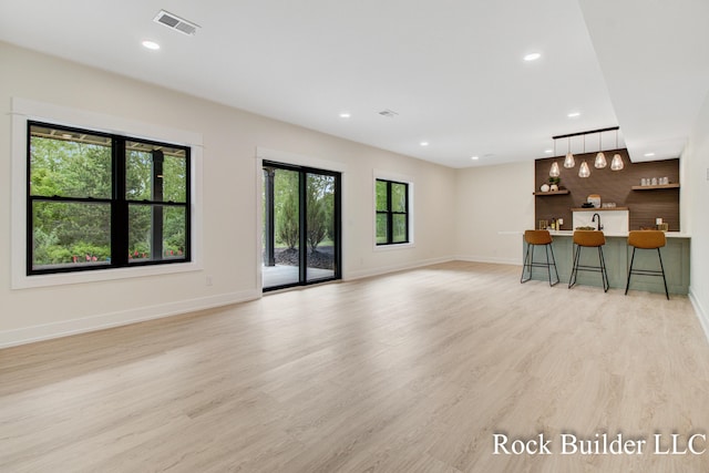 7134 Sugar Maple Dr, Hudsonville, MI 49426 - unfurnished living room featuring light wood-style floors, baseboards, recessed lighting, and bar
