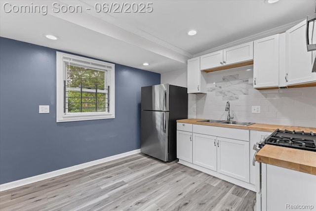 18697 Sunderland Rd, Detroit, MI 48219 - kitchen featuring wooden counters, freestanding refrigerator, a sink, light wood-type flooring, and backsplash