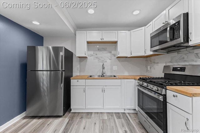 18697 Sunderland Rd, Detroit, MI 48219 - kitchen featuring stainless steel appliances, butcher block countertops, a sink, white cabinetry, and light wood-type flooring