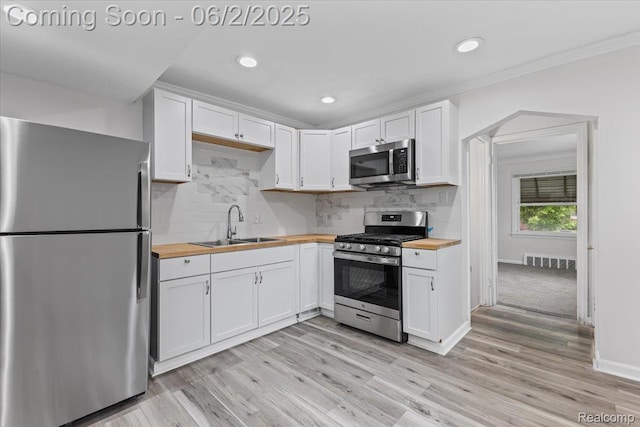 18697 Sunderland Rd, Detroit, MI 48219 - kitchen featuring stainless steel appliances, butcher block counters, a sink, white cabinets, and ornamental molding