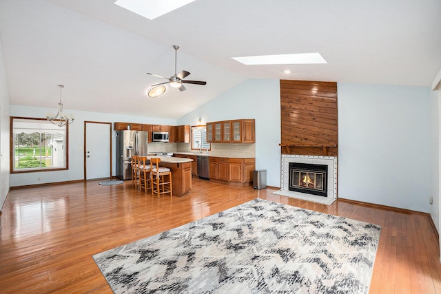 6400 Chestnut Hill Ct, Clarkston, MI 48346 - living area with a skylight, a tile fireplace, baseboards, light wood-style floors, and high vaulted ceiling