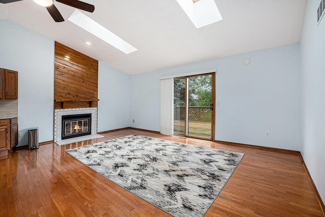 6400 Chestnut Hill Ct, Clarkston, MI 48346 - unfurnished living room featuring a skylight, vaulted ceiling, hardwood / wood-style flooring, a fireplace, and baseboards