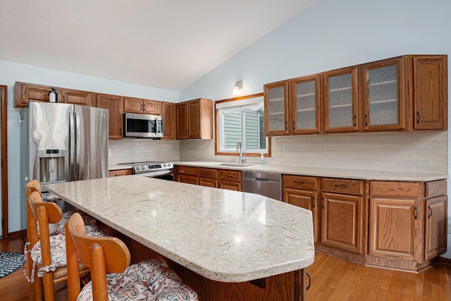 6400 Chestnut Hill Ct, Clarkston, MI 48346 - kitchen with stainless steel appliances, a sink, lofted ceiling, a kitchen breakfast bar, and light wood-style flooring