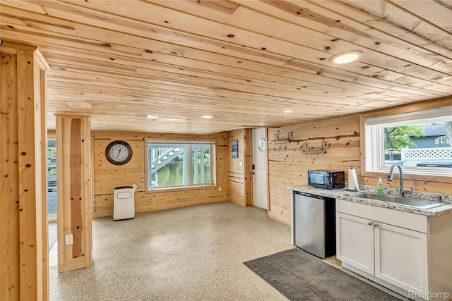533 Bellevue Ave, Lake Orion, MI 48362 - kitchen featuring fridge, black microwave, wood ceiling, wood walls, and white cabinetry
