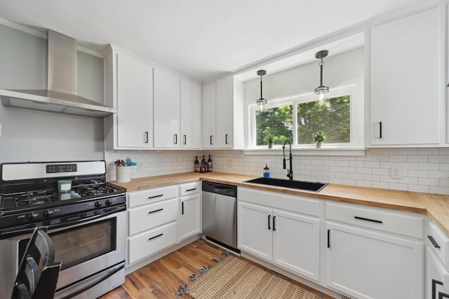 229 Water St, Grass Lake, MI 49240 - kitchen featuring appliances with stainless steel finishes, wood counters, wall chimney exhaust hood, and a sink