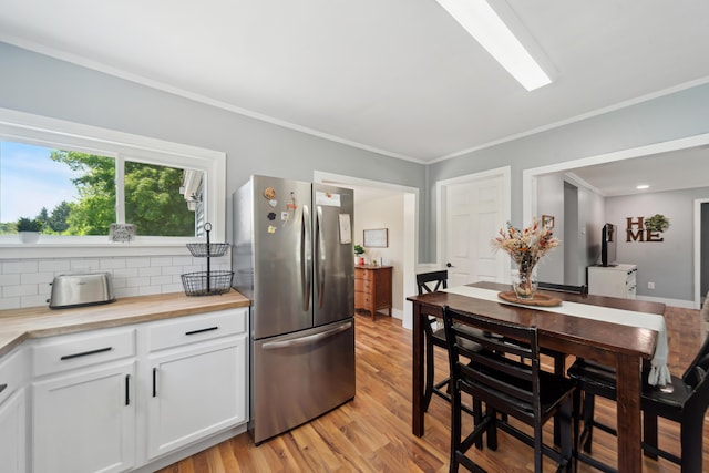 229 Water St, Grass Lake, MI 49240 - kitchen with freestanding refrigerator, light wood-style floors, white cabinetry, decorative backsplash, and crown molding