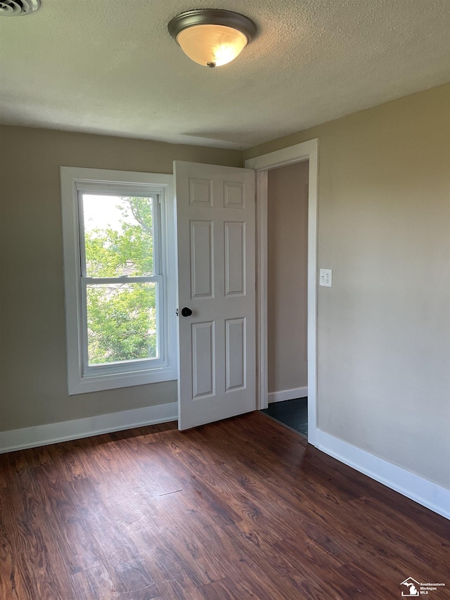 18200 Sherman, Milan, MI 48160 - unfurnished bedroom featuring dark wood finished floors, baseboards, and a textured ceiling