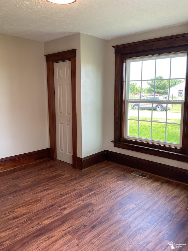 18200 Sherman, Milan, MI 48160 - empty room with dark wood-type flooring, baseboards, and a textured ceiling