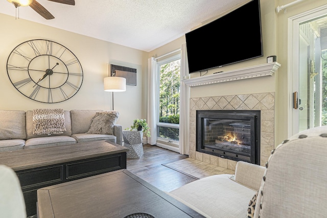 5737 Hilltop Way, Williamsburg, MI 49690 - living room featuring wood finished floors, a ceiling fan, a fireplace, a textured ceiling, and a wall mounted air conditioner
