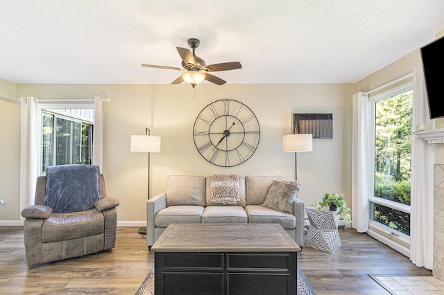 5737 Hilltop Way, Williamsburg, MI 49690 - living room featuring ceiling fan, wood finished floors, a wall unit AC, a tile fireplace, and a textured ceiling