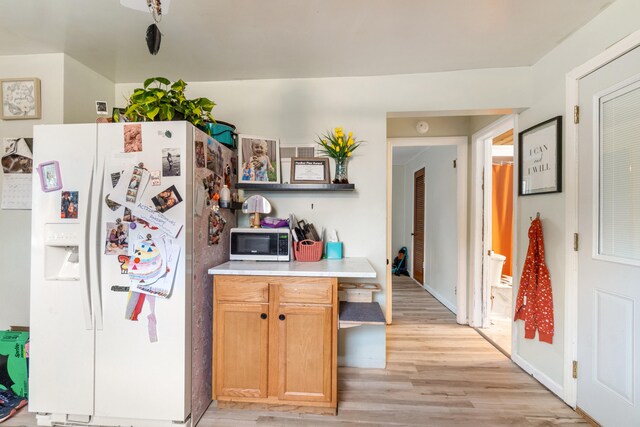 111 Greenleaf St, Onsted, MI 49265 - kitchen featuring white refrigerator with ice dispenser, stainless steel microwave, light wood-style flooring, and light countertops