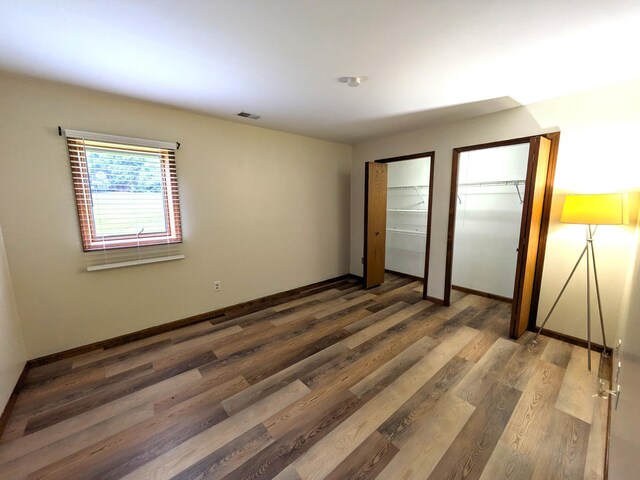 599 Echo Ct, Saline, MI 48176 - unfurnished bedroom with multiple closets, wood finished floors, and baseboards