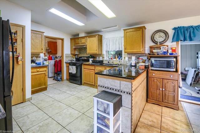 355 Carpenter Rd, Fostoria, MI 48435 - kitchen with black appliances, a sink, under cabinet range hood, a peninsula, and decorative backsplash