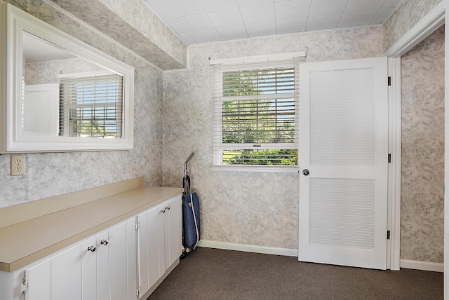 6130 Eidson Rd, Saint Joseph, MI 49085 - kitchen featuring dark carpet, light countertops, white cabinets, wallpapered walls, and baseboards