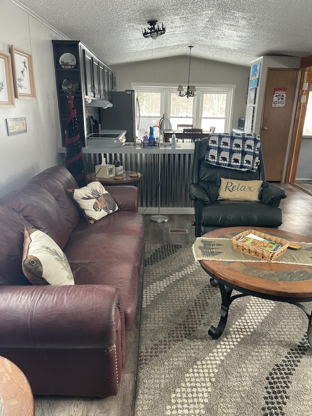 11064 S Hulbert Rd, Hulbert, MI 49748 - living room featuring vaulted ceiling, a chandelier, wood finished floors, and a textured ceiling